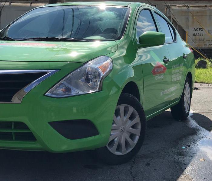 Green SERVPRO car outside of a commercial building 